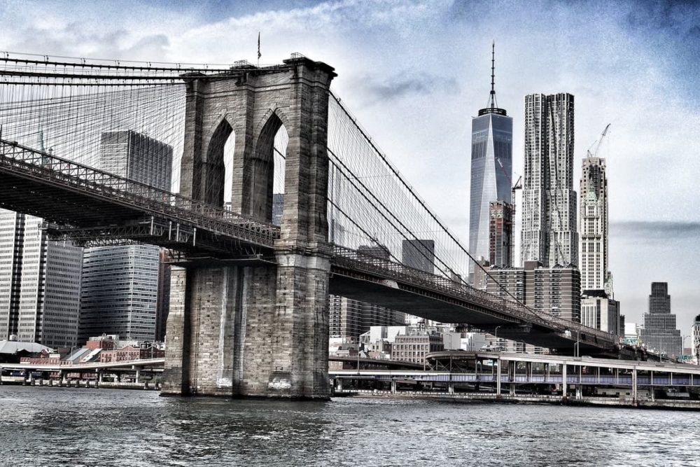 Brooklyn Bridge spanning East River across the backdrop of Manhattan's imposing skyline