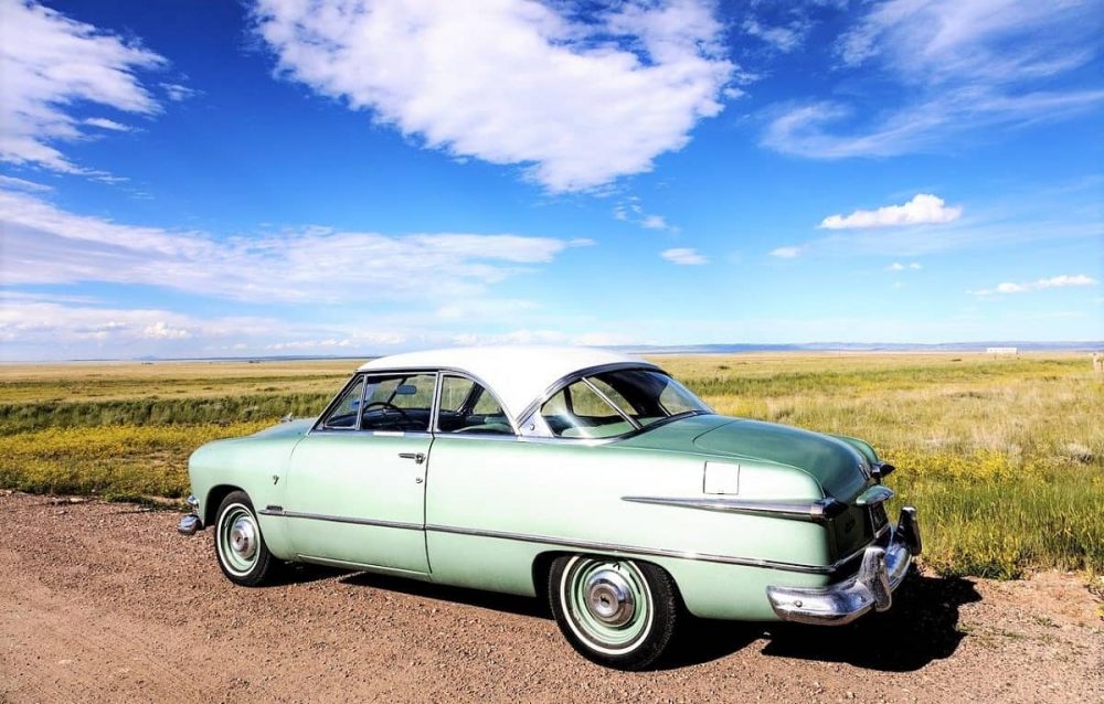 Historic car parked among open fields in Laramie