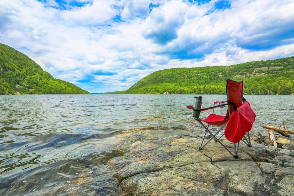 Empty red beach chair on rocks at Jordan Pond in Acadia National Park, Maine