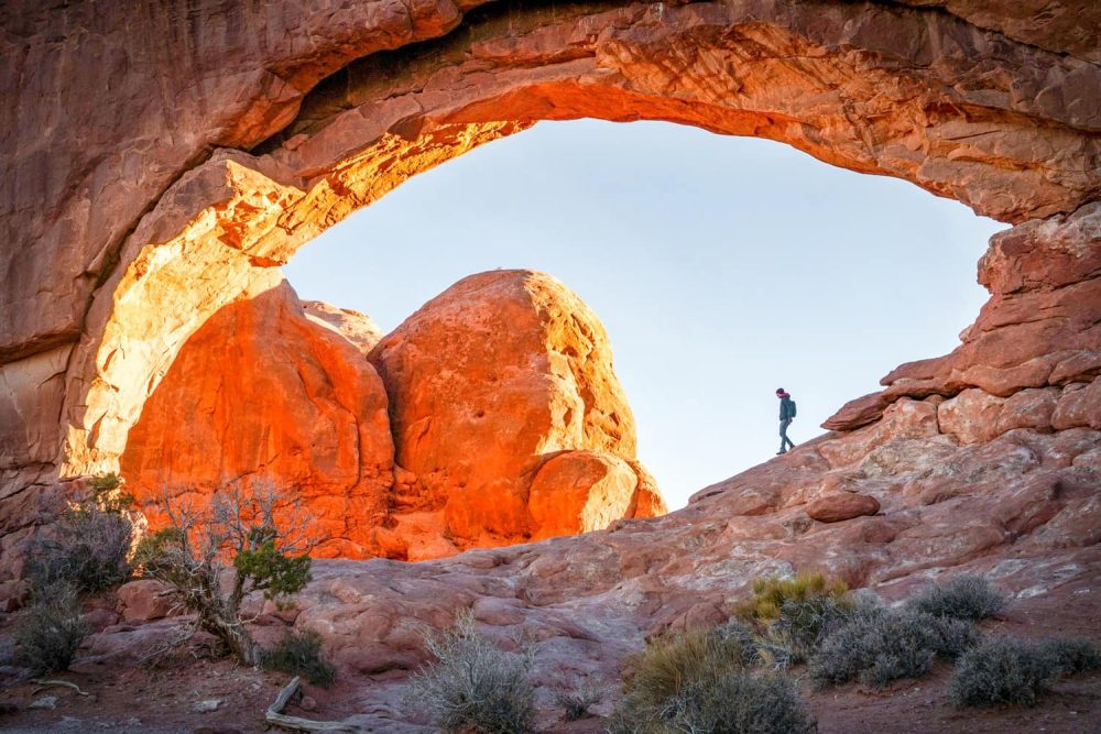 Person walking under mammoth arch in Arches National Park