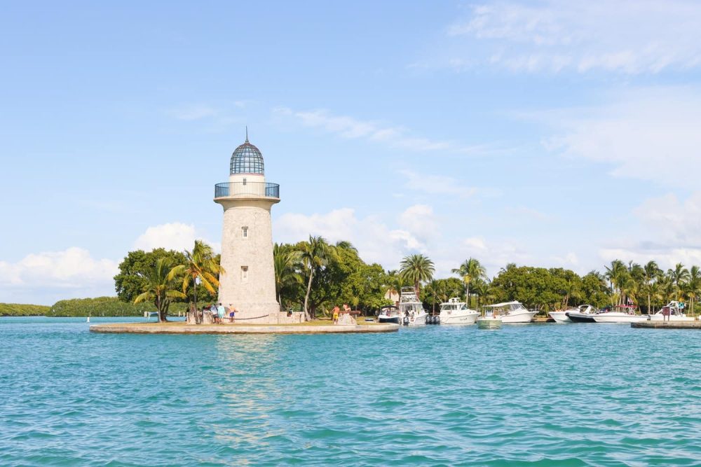 Grey lighthouse on narrow land strip shooting out into blue water in Biscayne National Park