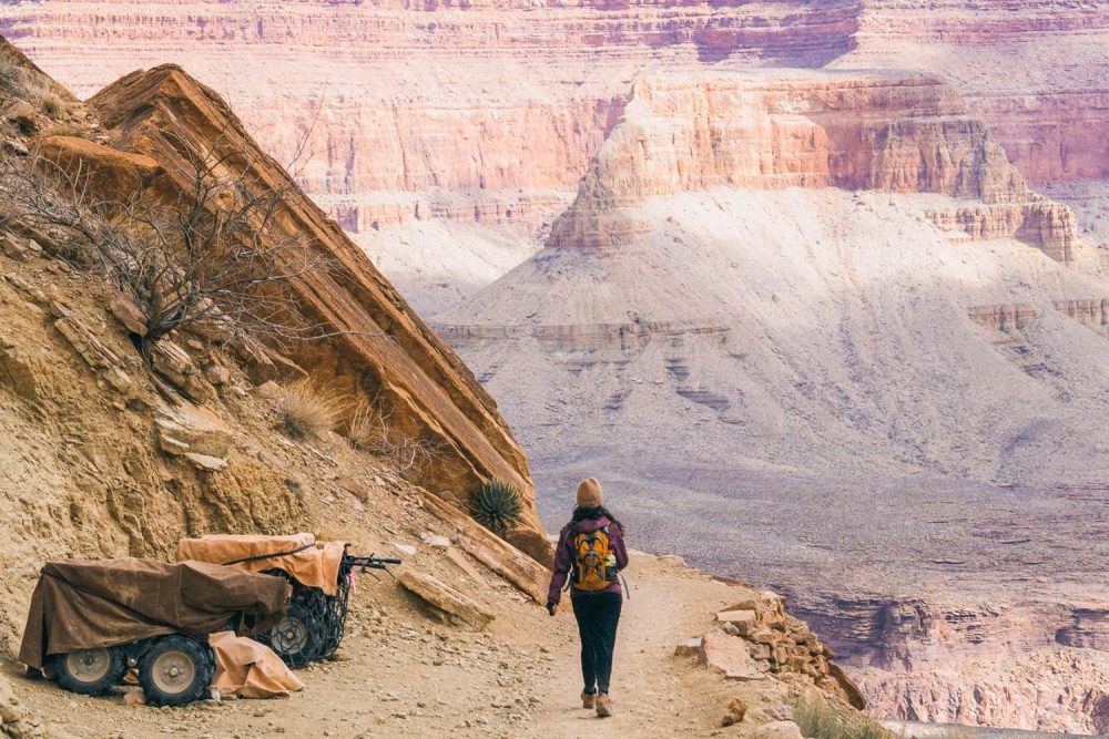 Woman with a winter hat on a trail leading into the Grand Canyon