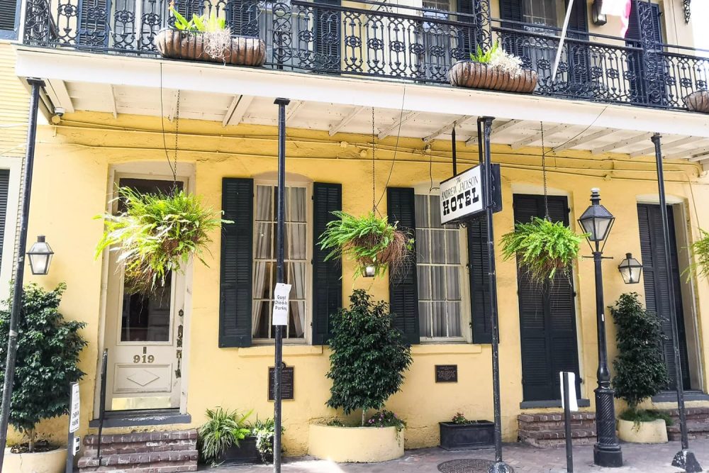 The French Quarter's historic Andrew Jackson Hotel with its stately iron balcony and dark window shutters against the bright facade